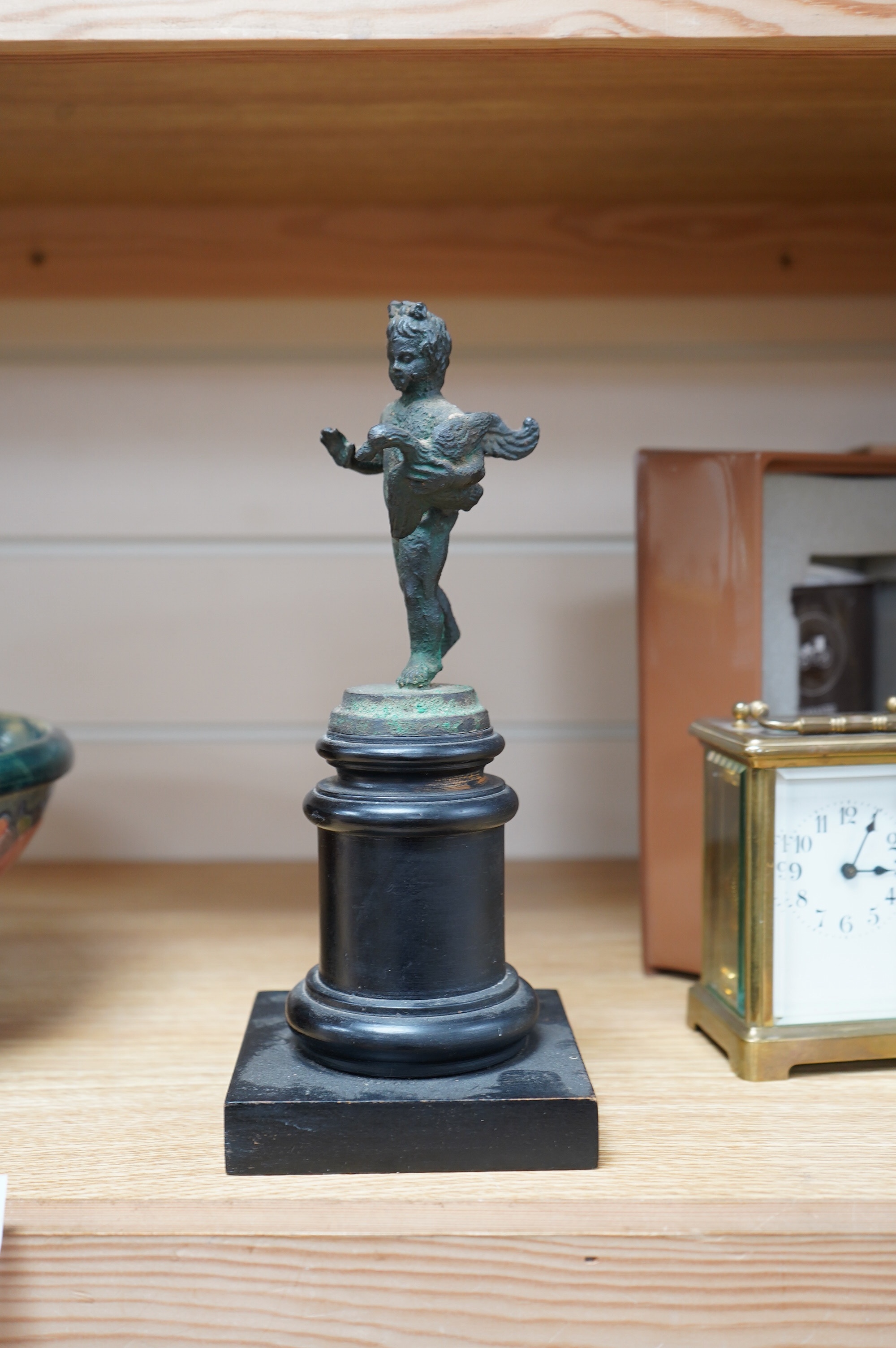 A bronze model of a putto, possibly Roman, holding a duck, on a circular plinth, 24.5cm. Condition - fair to good.